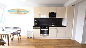 A modern kitchen with white cabinets, a built-in oven, and a coffee machine.