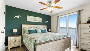 Un dormitorio con una cama de madera, una mesita de noche, un aparador y vistas al lago.