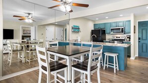 Una cocina moderna con una isla central, armarios blancos y un ventilador de techo.