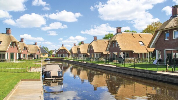 A canal lined with traditional houses with thatched roofs, a wooden dock, and a clear sky. - Lovely Home In Idskenhuizen - With Sauna (Idskenhuizen)
