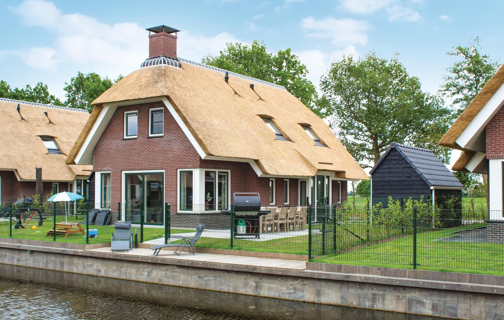 A traditional thatched-roof house with a brick facade, a chimney, and a small attached shed.
