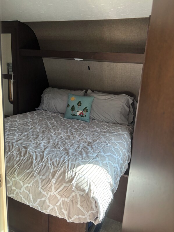 A bed with a patterned bedspread and a single decorative pillow.