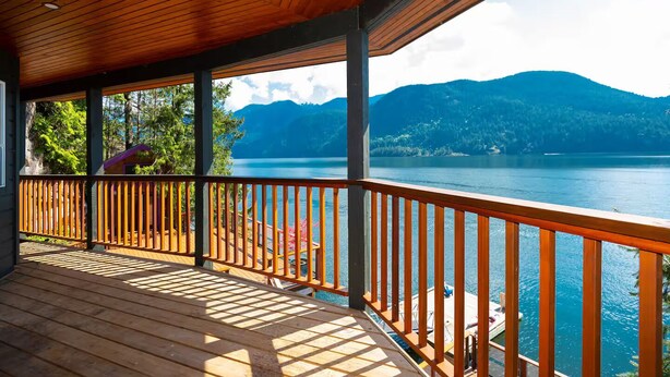 Een houten terras met uitzicht op een meer en bergen.