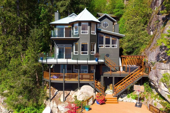 A multi-story house with a balcony, a staircase, and a basketball hoop.