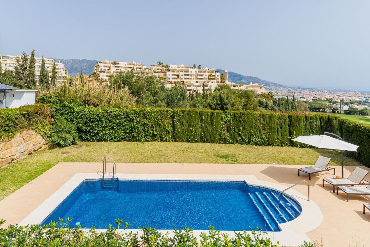A swimming pool with a view of a residential area and mountains in the background.