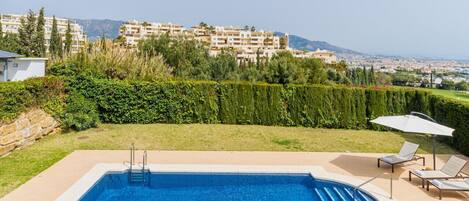 A swimming pool with a view of a residential area and mountains in the background.