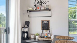A coffee station with a menu board, coffee maker, and various coffee products. - The Lazy Loft Stay for 4! (Branson)