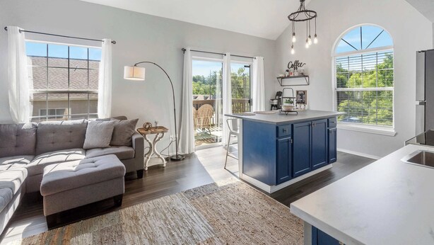 A modern kitchen with a large island, a dining area with a sofa, and a view of the outdoors. - The Lazy Loft Stay for 4! (Branson)