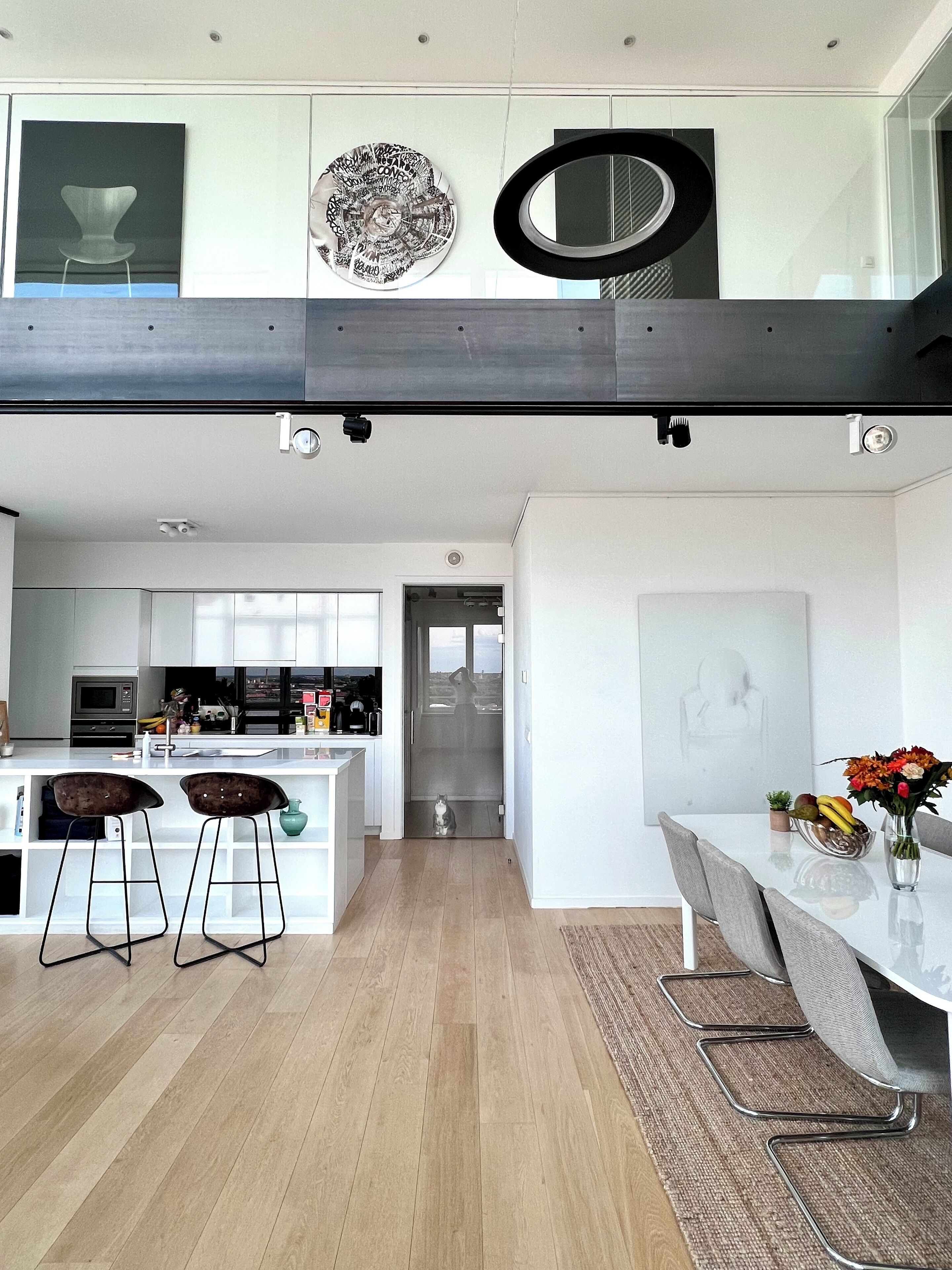 A modern kitchen with a central island, bar stools, and a dining area with a table and chairs.