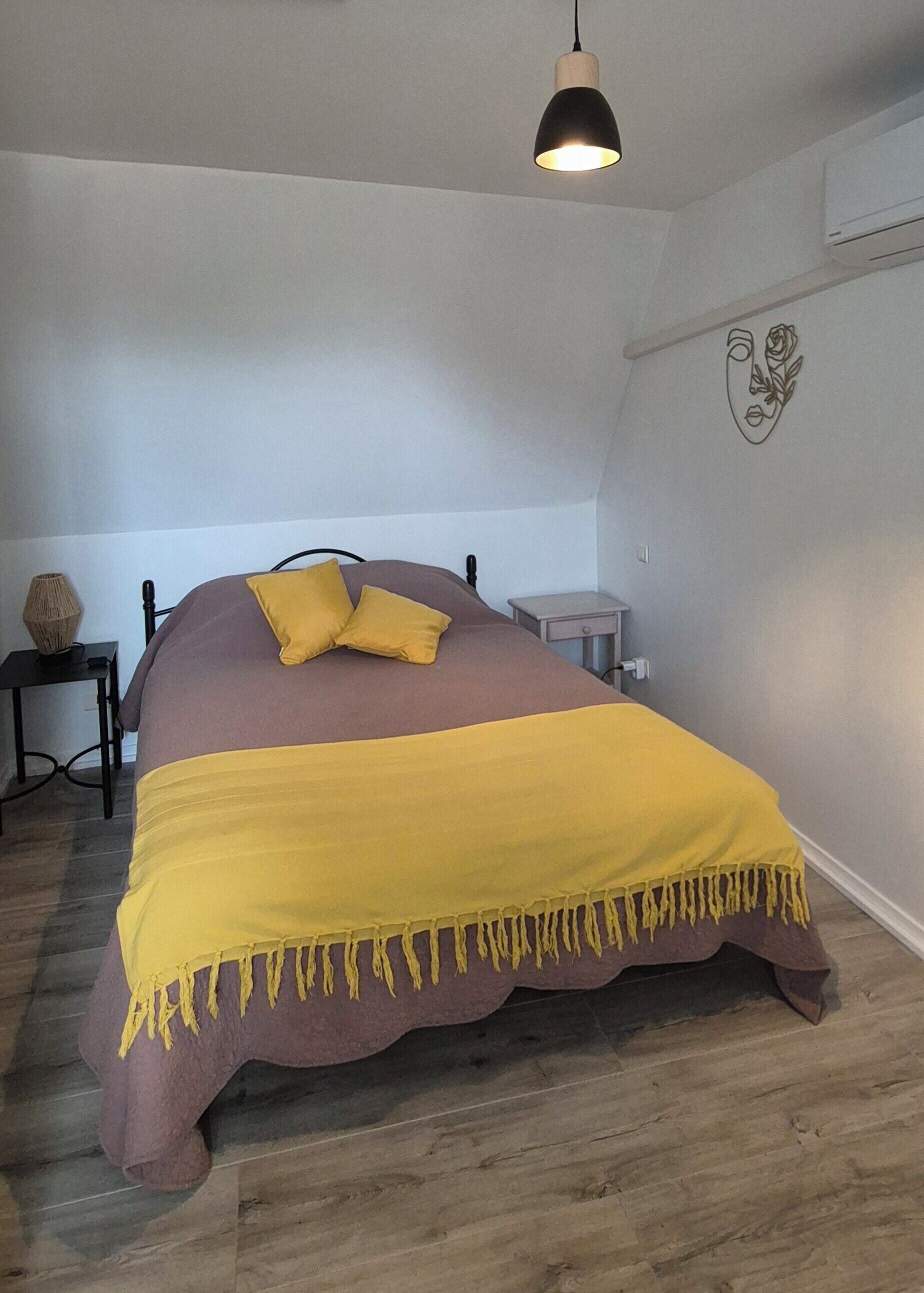 Quarto com cama, mesa de cabeceira, abajur e um ornamento na parede.