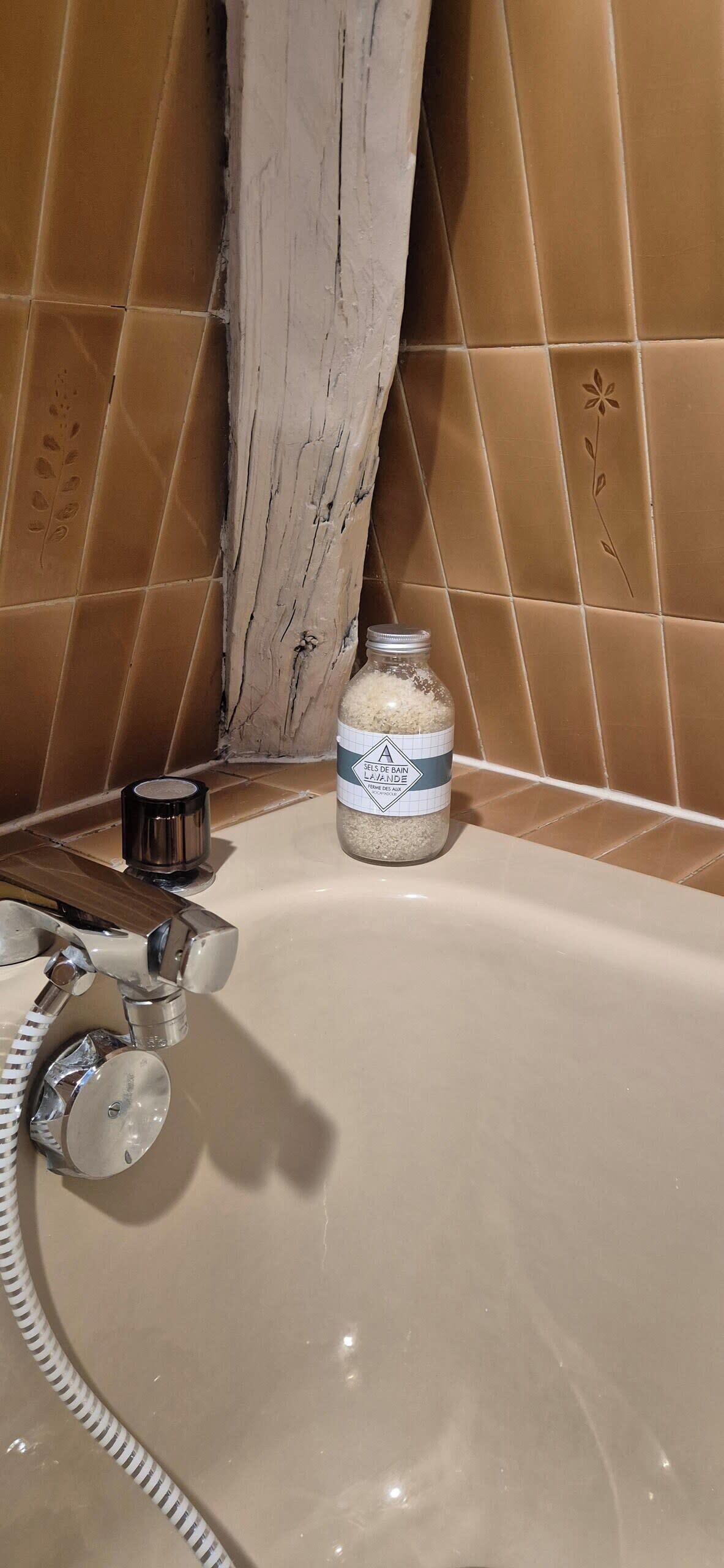 A bathroom with a bathtub, a jar of bath salts, and a towel rack.