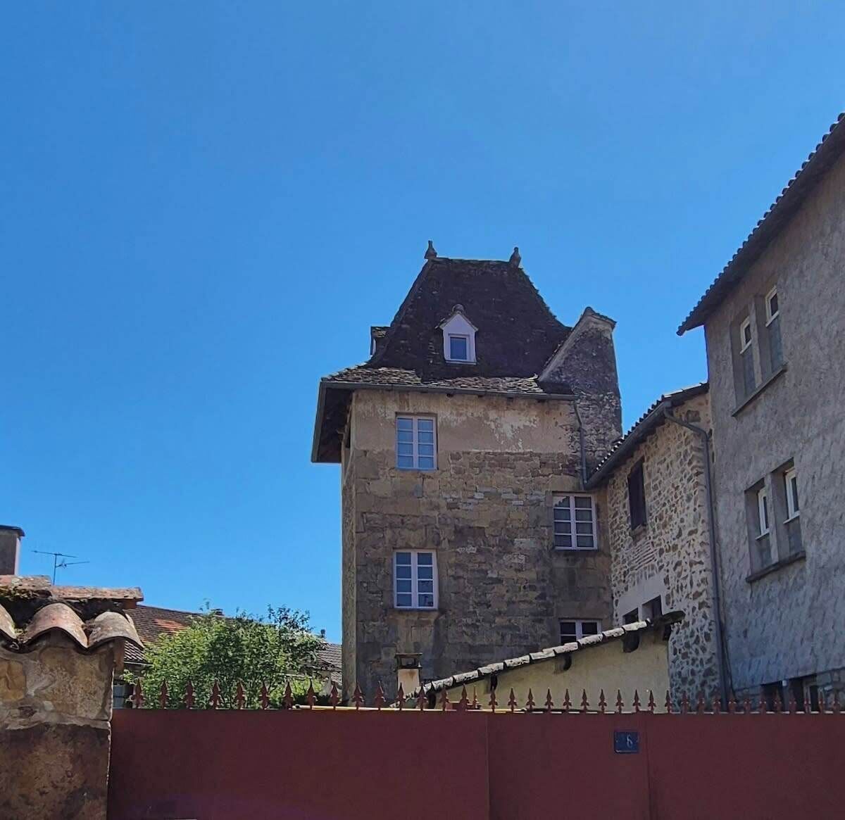 Un bâtiment en pierre doté d’un toit à forte pente et de nombreuses fenêtres.