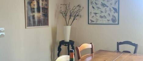 Une table à manger avec des chaises, une bouteille de vin, un verre et une boîte de crackers.
