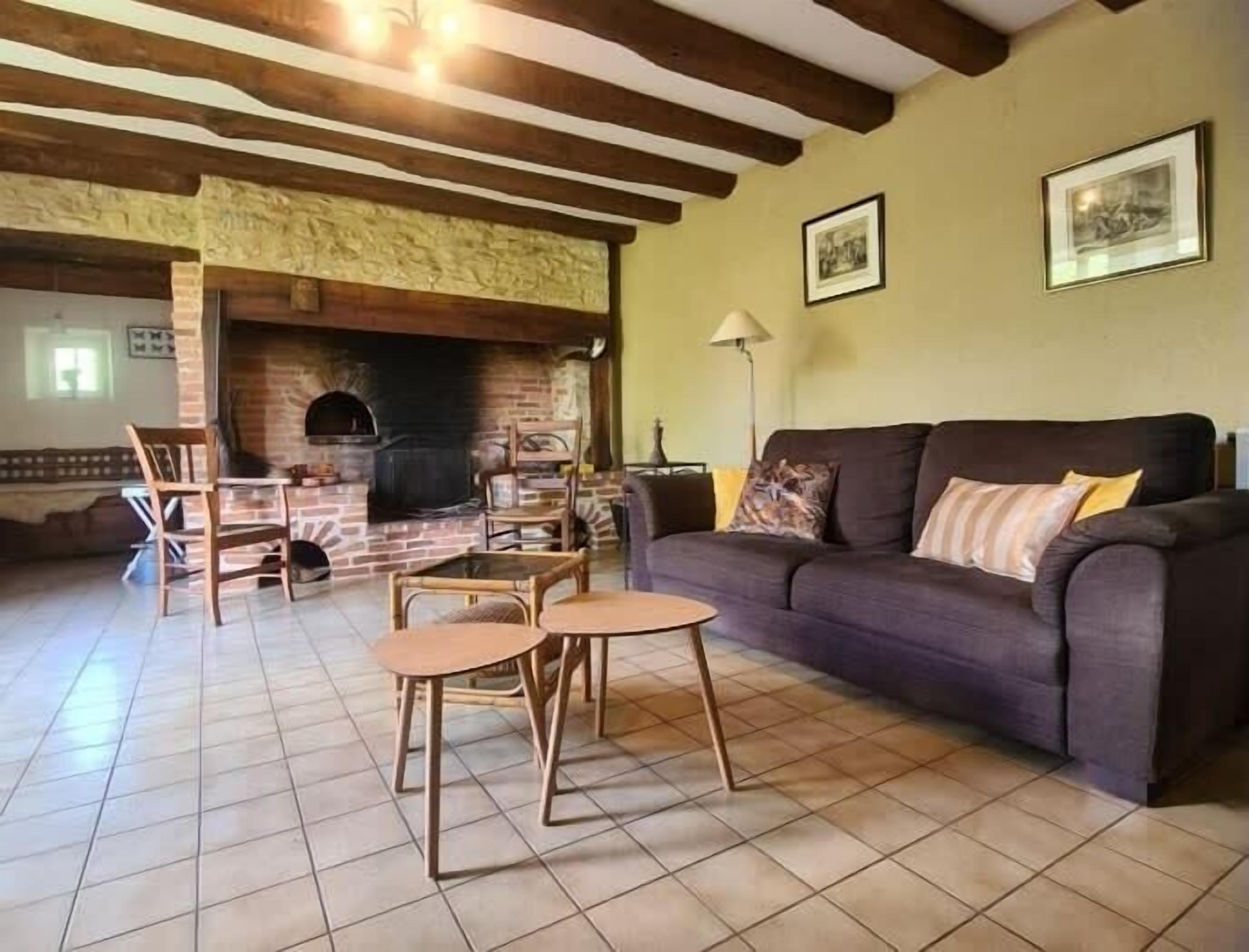 A living room with a brick fireplace, a sofa, and two chairs.