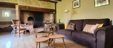A living room with a brick fireplace, a sofa, and two chairs.