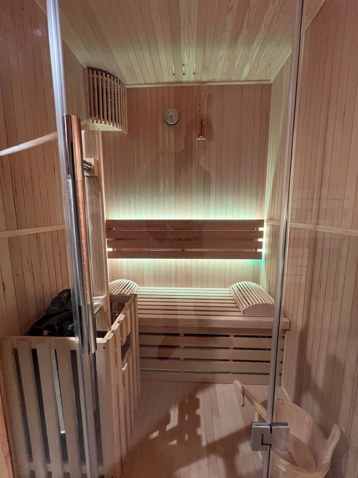 Un sauna avec des murs et des bancs en bois, une horloge et un système de ventilation.