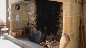 A stone fireplace with a television screen, a basket, and a chair.