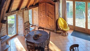 A rustic dining area with a wooden table and chairs, a large wooden cabinet, and a yellow chair.