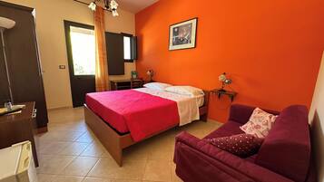 A bedroom with a bed, a desk, a chair, a sofa, a TV, and a painting on the wall.