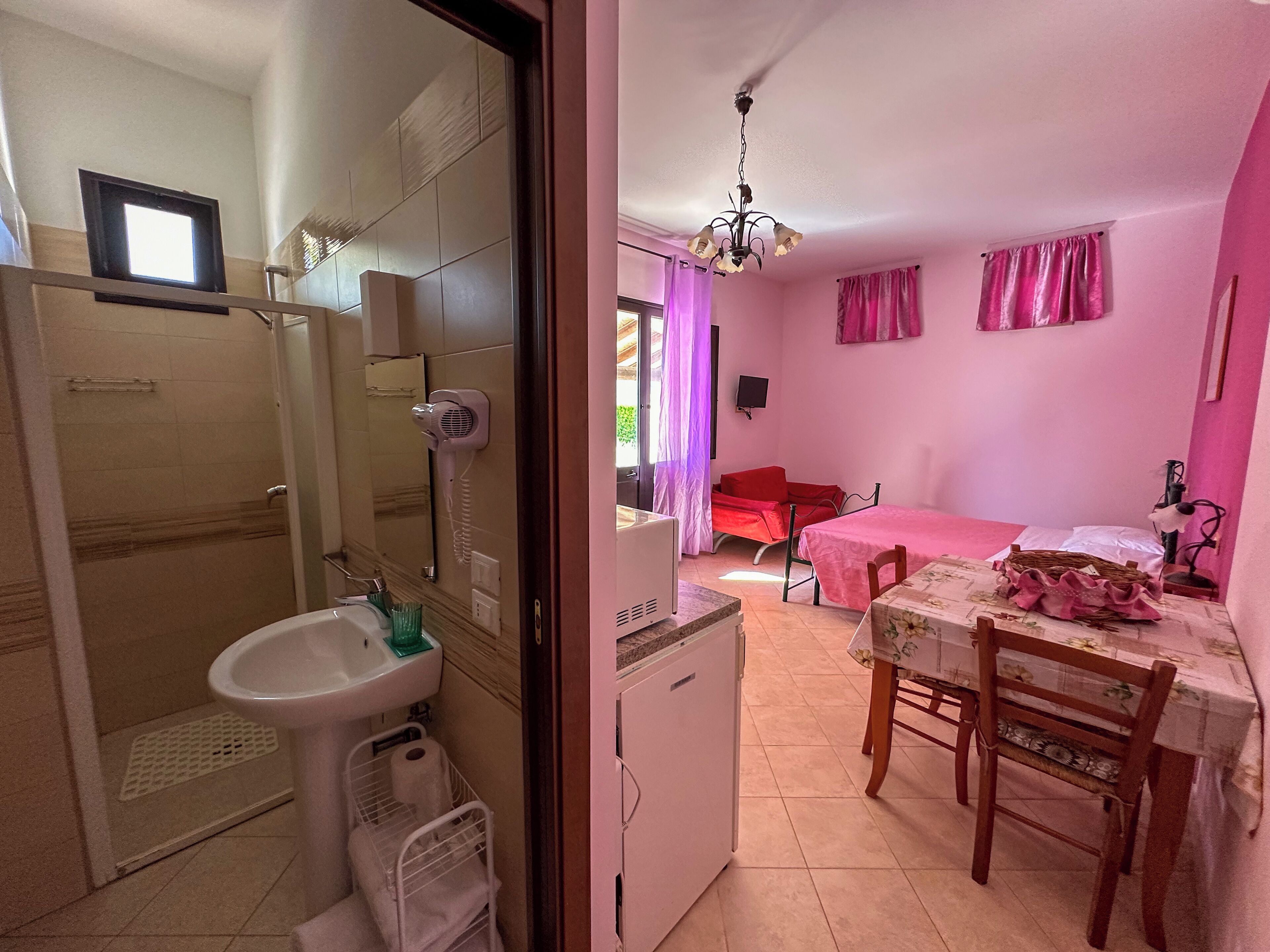 A compact room with a shower, sink, and a small table with chairs.