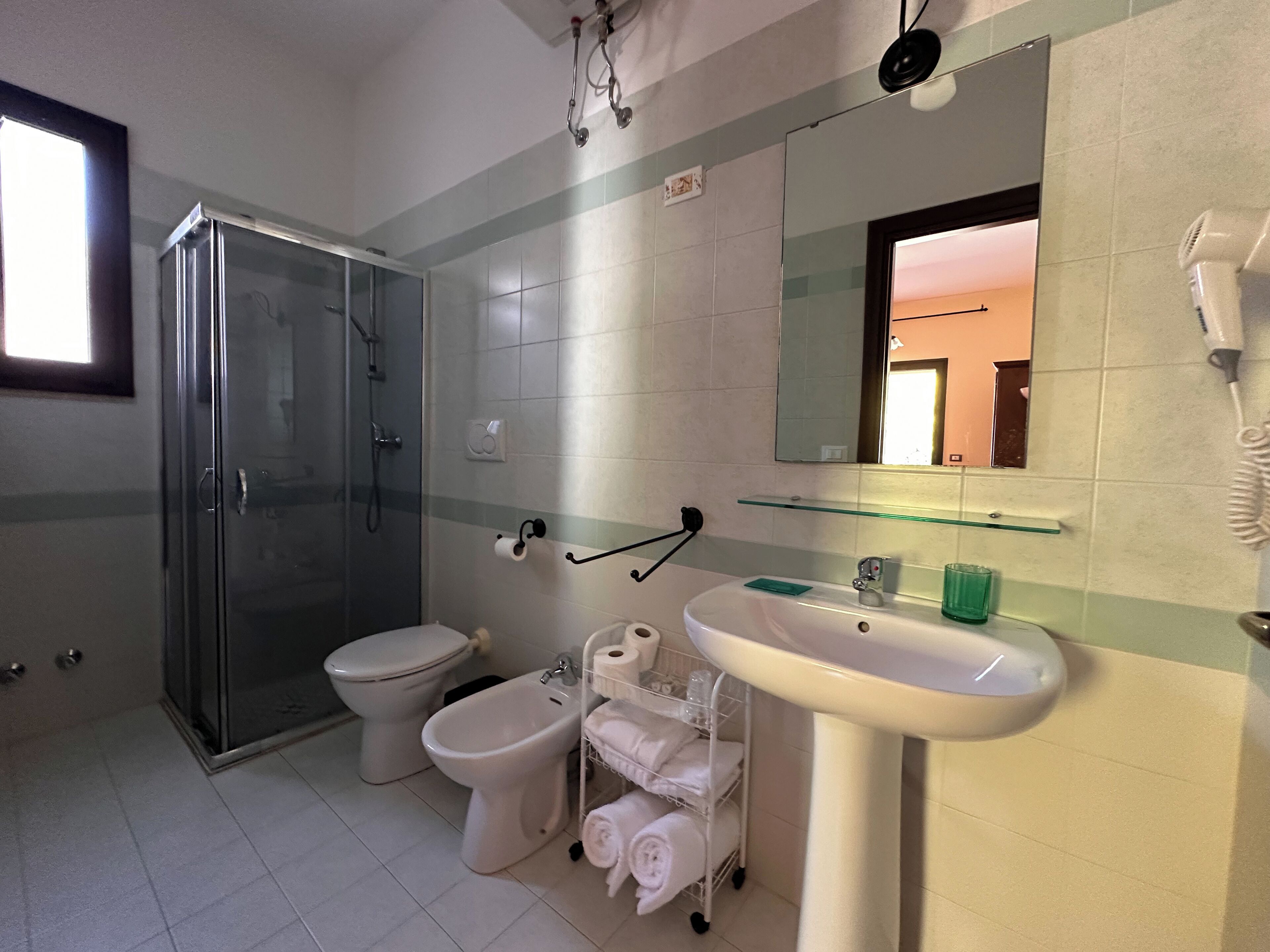 Une salle de bain moderne avec une douche à parois de verre, des toilettes, un bidet et un lavabo avec un miroir au-dessus.