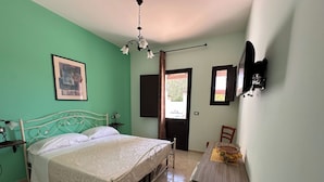 A bedroom with a bed, a bedside table, a chair, a desk, a hanging light fixture, and a window with curtains. - LA PALMA VACANZE (Sogliano Cavour)