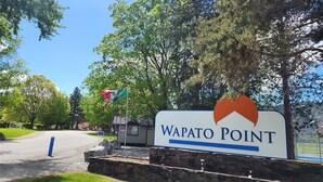 Señal de Wapato Point con un logotipo, una bandera y un muro de piedra.