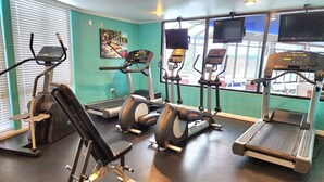 Un gimnasio con cintas de correr, elípticas y una banca para pesas.