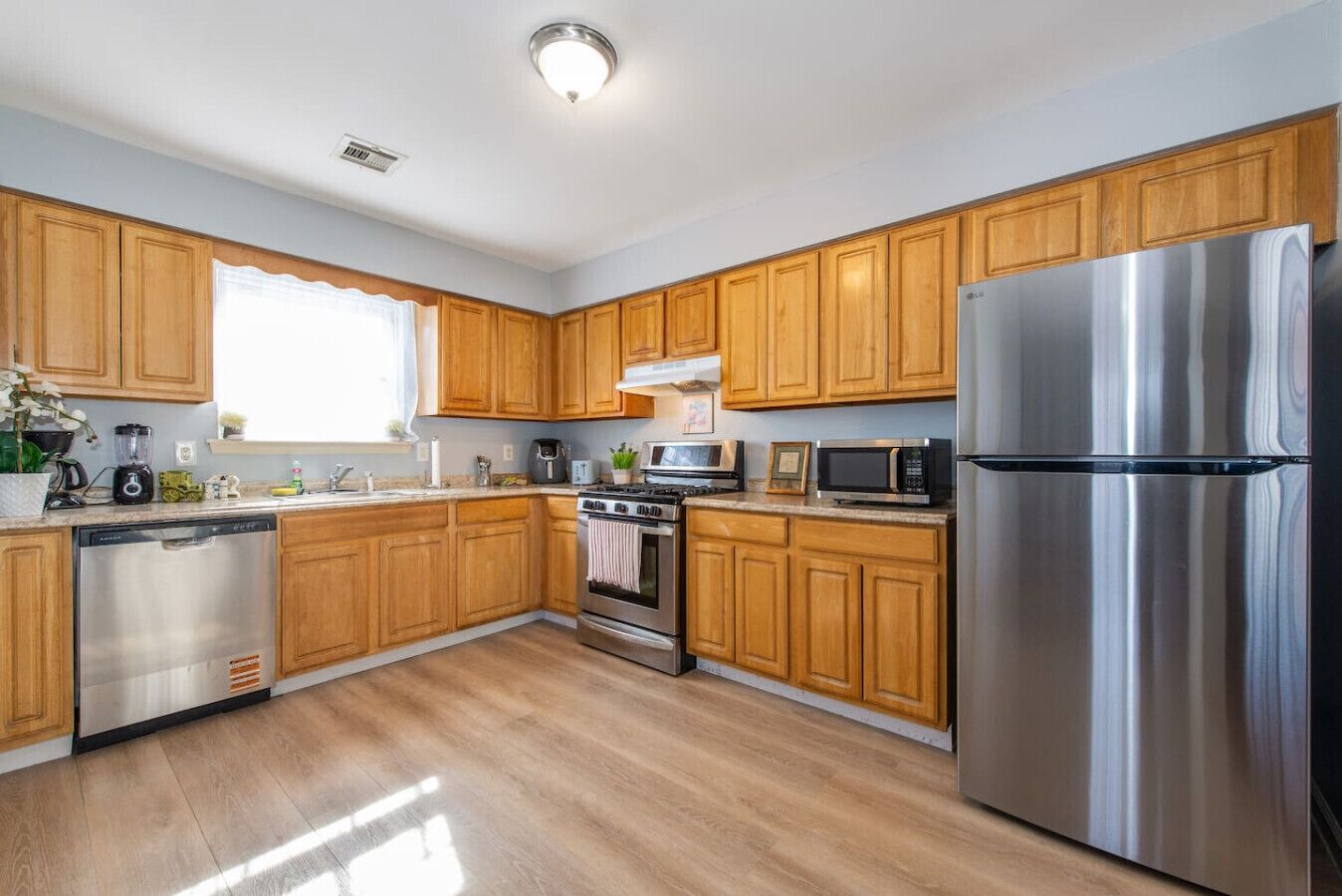 A modern kitchen with wooden cabinets, stainless steel appliances, and a dishwasher.