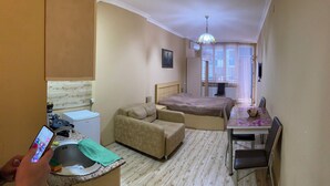 A compact hotel room with a bed, a sofa, a dining table, and a small kitchenette. - horizont building (Batumi)