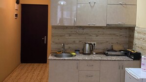 A compact kitchen with a sink, stove, and cabinets. - horizont building (Batumi)