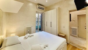 Ein Schlafzimmer mit Bett, Kleiderschrank, Heizkörper und einer Tür, die auf einen Balkon führt.