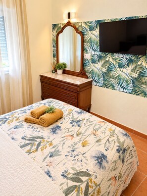Een hotelkamer met een bed, een dressoir, een spiegel, een televisie en een raam met gordijnen.