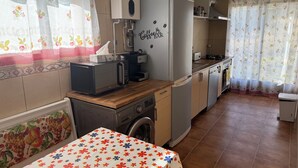 Une cuisine compacte équipée d’un lave-linge, d’une machine à café et d’un réfrigérateur.