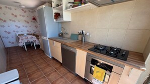 Une cuisine compacte équipée d’un lave-vaisselle, d’une cuisinière, d’un four et d’un petit évier.