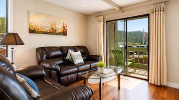 A living room with a leather sofa, a glass coffee table, and a painting on the wall.