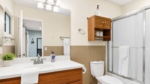 Une salle de bain moderne avec un meuble-lavabo en bois, un grand miroir, des toilettes et une cabine de douche en verre.