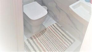 A bathroom with a toilet, a shower, and a sink.