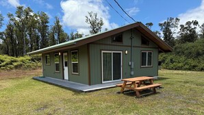 Une petite cabane à un seul étage, dotée d’un porche à l’avant et d’une table de pique-nique.