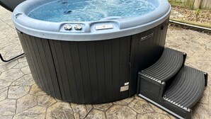 A hot tub with a control panel and steps, placed on a stone patio. - *Close to the Falls*Hot Tub*Easy Checkout*Parking* (Niagara Falls)