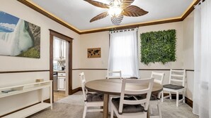 A dining area with a round table, white chairs, a ceiling fan, a world map artwork, and a green wall decoration. - *Close to the Falls*Hot Tub*Easy Checkout*Parking* (Niagara Falls)