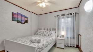 A bedroom with a bed, a nightstand, a ceiling fan, and a window with curtains. - *Close to the Falls*Hot Tub*Easy Checkout*Parking* (Niagara Falls)