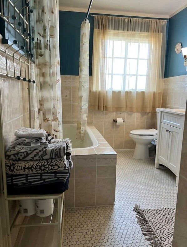A bathroom with a bathtub, toilet, and a shower curtain.