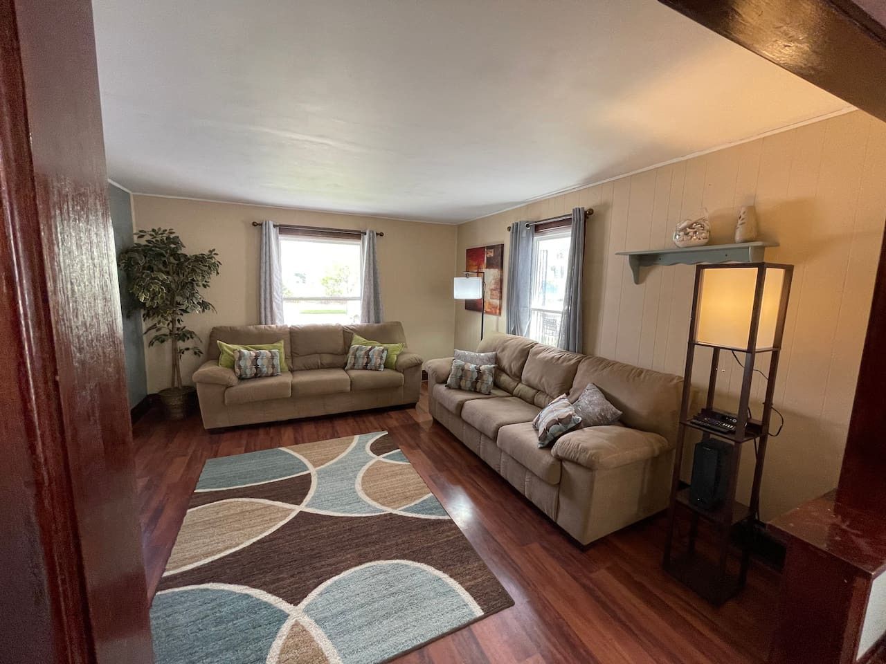 A living room with two sofas, a rug, a lamp, and a plant.