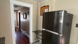 Cocina con refrigerador de acero inoxidable, repisa de vidrio y puerta que da a otra habitación.