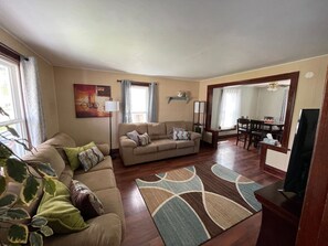 Ein Wohnzimmer mit einer Couch, einem Esstisch und einem Fernseher.