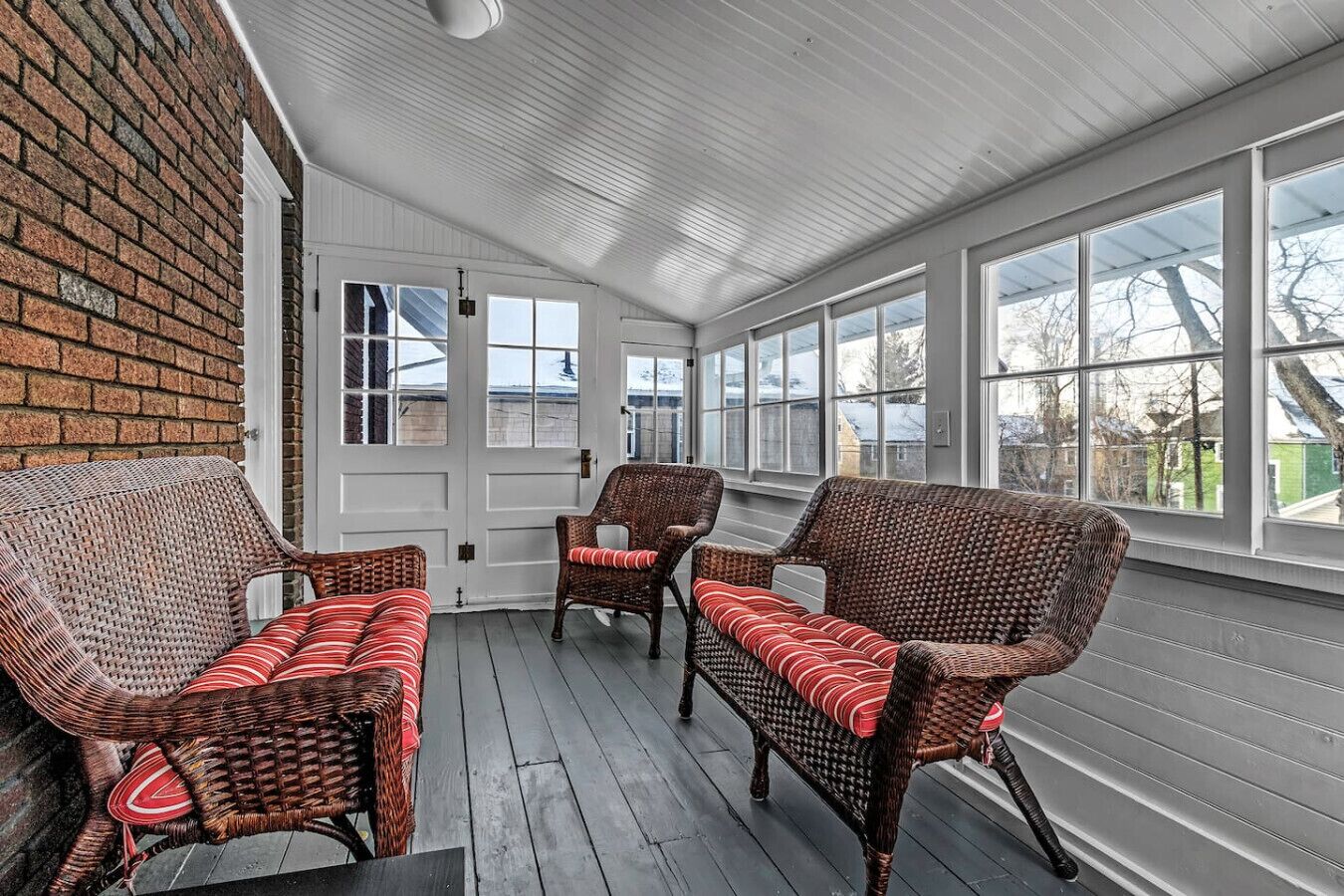 A covered porch with wicker furniture and a brick wall.