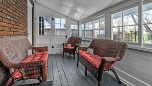 A covered porch with wicker furniture and a brick wall. - Spacious ♥ Niagara Falls♥A/C♥Parking♥Steam Shower (Niagara Falls)