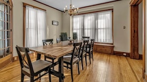 A dining room with a wooden table and chairs, large windows with sheer curtains, and a chandelier. - Spacious ♥ Niagara Falls♥A/C♥Parking♥Steam Shower (Niagara Falls)