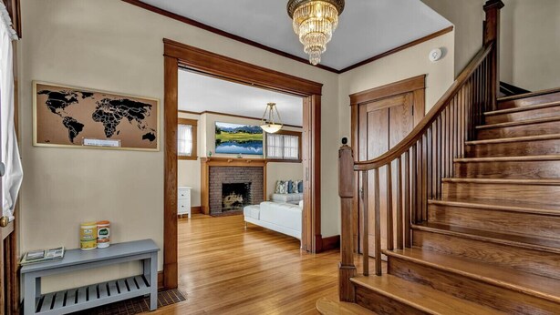 A wooden staircase leading to a living area with a fireplace, a bench, and a world map on the wall. - Spacious ♥ Niagara Falls♥A/C♥Parking♥Steam Shower (Niagara Falls)